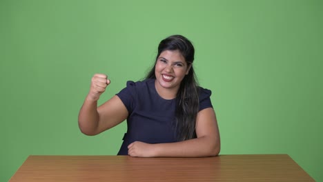 Young-overweight-beautiful-Indian-businesswoman-against-green-background