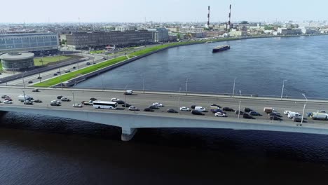 Brücke-über-den-großen-Fluss-mit-blauem-Wasser-und-Barge-pullin-in-der-Großstadt