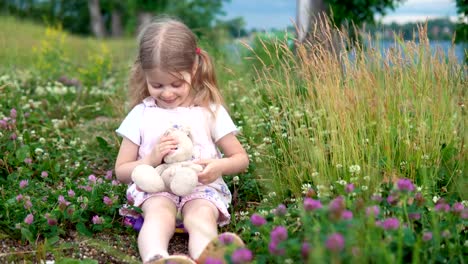 Una-niña-jugando-con-un-conejo-de-juguete-en-el-Prado-entre-el-trébol-de-flores