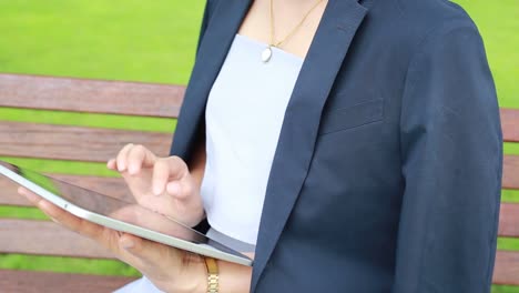 Young-attractive-woman-with-tablet-computer-sitting-in-garden