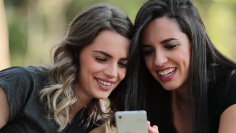 Candid-Girlfriends-looking-at-their-cellphone-outdoors-on-social-media