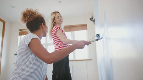 Zwei-Frauen,-die-Dekoration-der-Zimmer-im-neuen-Haus-Malerei-Wand-zusammen