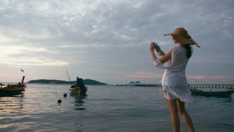 Beautiful-woman-taking-photos-with-smart-phone-technology-on-paradise-beach