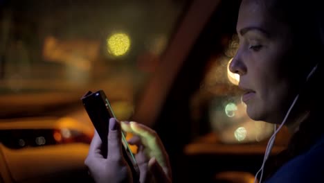 Retrato-de-la-joven-mujer-caucásica-hermosa-usando-la-mano-del-teléfono-inteligente-mantener-al-aire-libre-en-la-noche-de-la-ciudad,-sonriendo,-cara-iluminada-ScreenLight-red-social,-tecnología,-concepto-de-comunicación