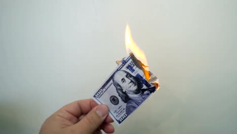 Hand-holding-a-burning-hundred-dollar-banknote