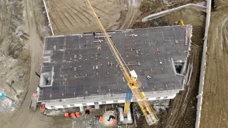 Construction-of-a-high-rise-building,-a-view-from-the-top-with-a-drone.-Workers-build-a-house.-Panorama-from-the-top-of-the-construction-site