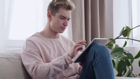 Man-using-digital-tablet-on-sofa-at-home