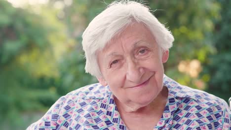 Portrait-of-an-elderly-woman.-The-elderly-person-in-the-nursing-home-and-the-green-of-the-trees-in-the-background.