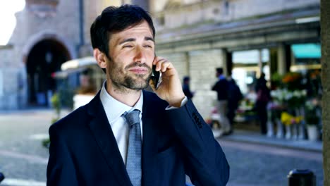 Un-hombre-de-negocios-contestar-el-teléfono,-enviar-mensajes-y-sonrisas-para-las-hermosas-noticias-de-trabajo-y-en-el-fondo-se-ve-a-un-pueblo.