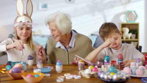 Grandmother-and-Grandchildren-Decorating-Eggs-and-Smiling