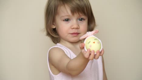 Retrato-de-la-chica-linda-rubia-sonriente-tiene-huevo-de-pollo-decorado-para-la-chica-de-Pascua,-el-hocico-pintado-y-el-arco.