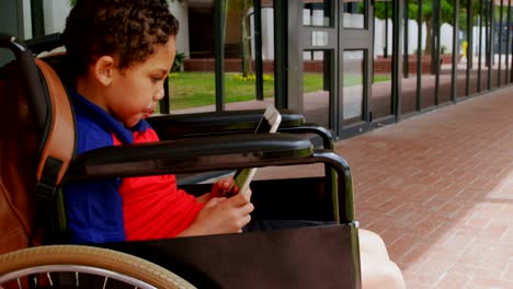 Side-view-of-disabled-African-American-schoolboy-using-digital-tablet-in-school-corridor-4k