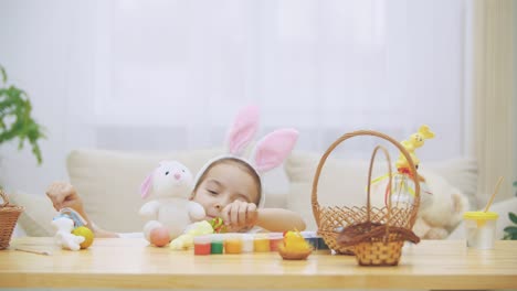 Little-cute-and-adorable-girl-is-smiling-and-playing-with-colorful-chicken's-eggs-and-bunnies.-Concept-Easter-holiday.