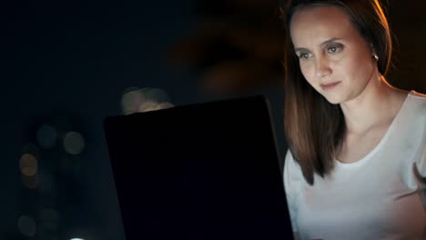 Jovencita-noche-de-verano-sentada-en-la-hierba-con-Laptop-en-la-ciudad