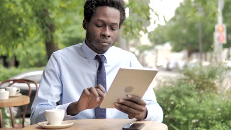 Hombre-de-negocios-africano-usando-la-tableta,-sentado-en-al-aire-libre-Cafe