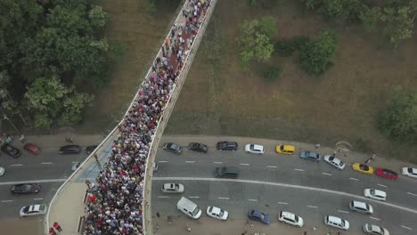 A-crowd-of-people-on-a-pedestrian-bridge-in-the-spring-evening.-Aerial-view.-A-new-bicycle-pedestrian-bridge-in-the-center-of-the-capital-of-Ukraine,-the-city-of-Kiev.-Excursions-and-walks-for-tourist