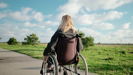 Mujer-adulta-discapacitada-está-conduciendo-su-silla-de-ruedas-en-el-área-del-parque-en-un-día-soleado