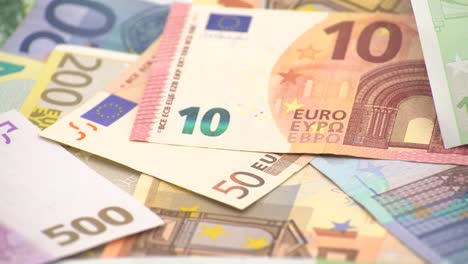 4K-Primer-plano-de-una-moneda-de-un-euro-con-billetes-de-diferentes-valores.-Dinero-en-efectivo