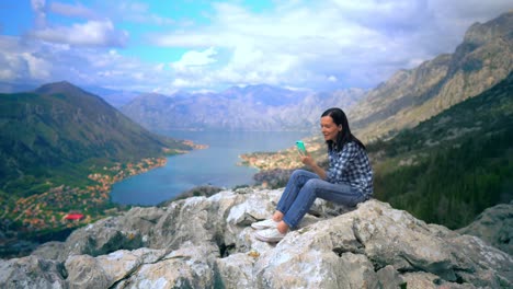 Junge-Frau-mit-Blick-auf-Smartphone-auf-Berggipfel