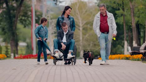 Guy-in-a-wheelchair-walks-with-his-family-along-the-avenue.-Family-support-for-people-with-disabilities.