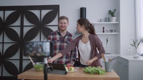 nutritional-blog,-vloggers-man-and-woman-prepare-healthy-breakfast-with-vegetables-and-greens-in-kitchen-while-camera-smartphone-records-video-for-subscribers-at-social-networks