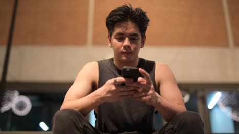 Young-handsome-Asian-man-using-phone-in-the-city-outdoors-at-night