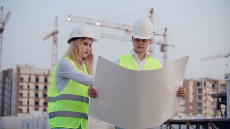 Mujer-hablando-por-teléfono-y-pregunta-al-Constructor-lo-que-está-en-los-dibujos-de-pie-en-el-fondo-de-los-edificios-en-construcción