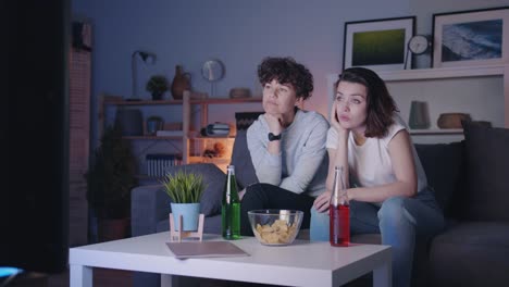 Weibliche-Freunde-beobachten-langweiligen-Film-im-Fernsehen-gähnend-sitzen-auf-der-Couch-in-der-Nacht