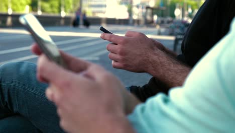 Hombres-que-usan-un-teléfono-inteligente-sentados-en-un-banco