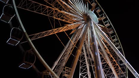 Riesenrad.-Ein-Riesenrad-dreht-sich-vor-dem-Hintergrund-des-Nachthimmels.-Nahaufnahme-eines-Riesenrades-mit-Nachtbeleuchtung.-beleuchtete-Riesenradkonstruktion,-die-sich-vor-dunklem-Nachthimmel-Hintergrund-dreht.