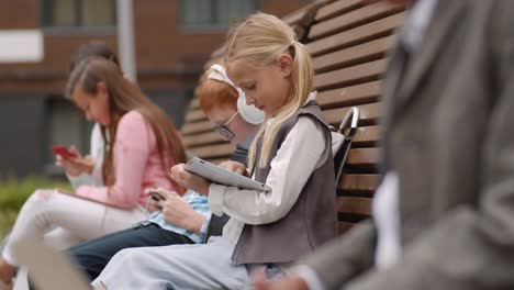 Blonde-Schulmädchen-mit-Tablet-im-Freien