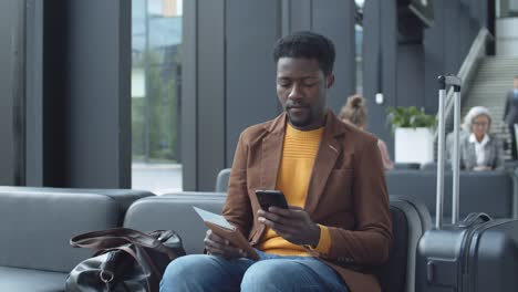 African-Man-Using-Cellphone-while-Waiting-in-Airport