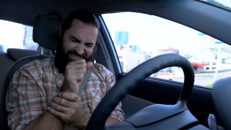 Bearded-man-massaging-wrist-while-driving-car,-injured-hand,-joint-inflammation