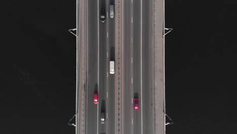 Bridge-highway-dark-water-red-blue-cars-traffic-aerial-top-view