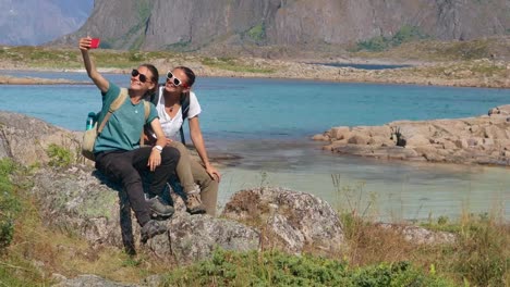 Two-young-women-bloggers-taking-a-selfie-with-a-view-to-a-Norwegian-fjord-with-a-smartphone.