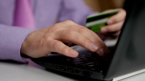 Un-hombre-de-negocios-con-camisa-y-corbata-morada-está-haciendo-un-pago-a-la-banca-por-Internet.-Compras-en-línea-con-tarjeta-de-crédito-en-el-ordenador-portátil.