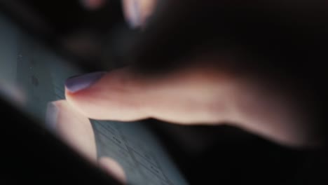 Close-up-hands-of-a-young-woman-in-a-dark-room-to-typing-text-on-the-touchscreen-of-the-tablet