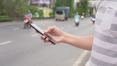 Hand-des-Mannes-mit-einem-Mobiltelefon-auf-der-Straße.-Nutzung-der-Transport-App