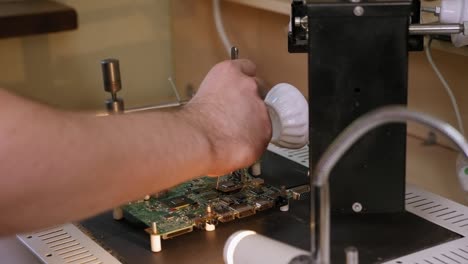 A-repairman-soldering-microchips-with-a-blow-dryer-while-repairing-a-computer.