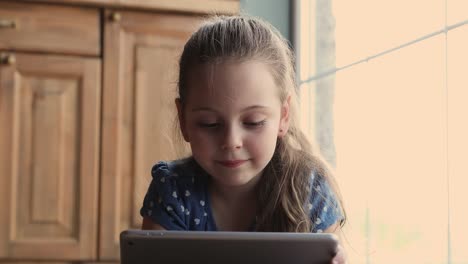 Close-up-view-little-girl-lying-indoor-with-tablet-device