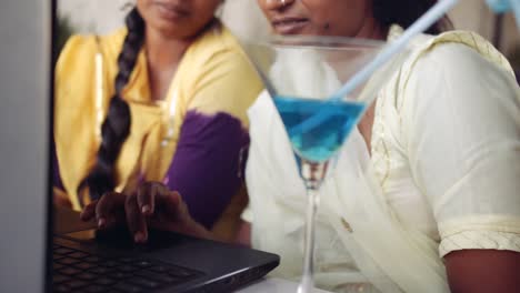 Two-women-chilling-sipping-drinks-using-technology-in-cafe