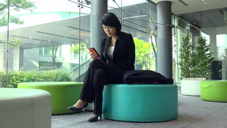 Business-Travel-Asiatische-Frau-Geschäftsfrau-mit-Smartphone-im-Bürogebäude