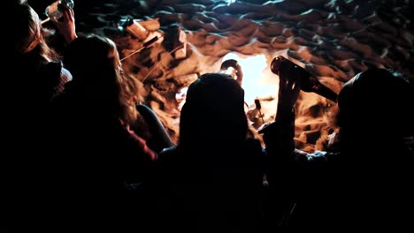 junges-Paar-Getränk-trinken-und-dabei-anstoßen-in-der-Nähe-von-Feuer-im-nächtlichen-Wald,-Liebhaber-trinken-Alkohol-und-macht-Toasten-im-freien-Glas,-Mann-mit-Mädchen-jubelt-Bier-in-Reisen-Camp-im-Wald