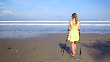 CLOSE-UP:-Starke,-unabhängige-Frau-mit-Krücken-auf-Sommerurlaub-am-Strand