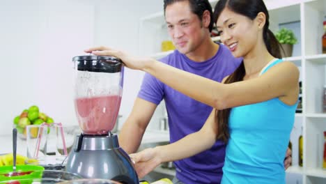 Étnica-mujer-hombre-con-jugo-fresco-de-cocina-licuadora