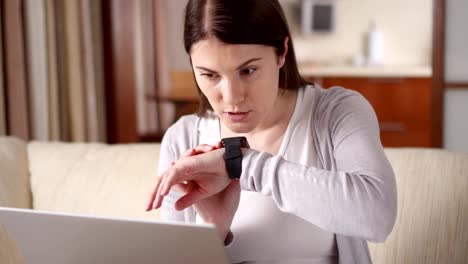 Mujer-en-casa-enviando-el-mensaje-de-audio-mediante-reloj-inteligente.-Joven-mujer-profesional-trabajando-en-smartwatch