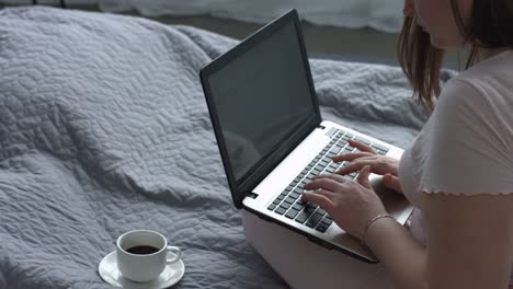 Positive-woman-with-laptop-blogging-on-the-bed