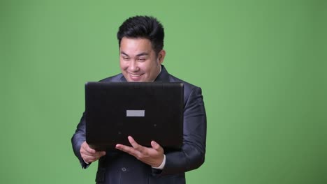 Young-handsome-overweight-Asian-businessman-against-green-background