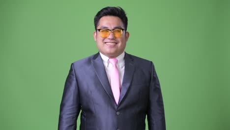 Young-handsome-overweight-Asian-businessman-against-green-background