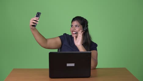 Young-overweight-beautiful-Indian-businesswoman-against-green-background